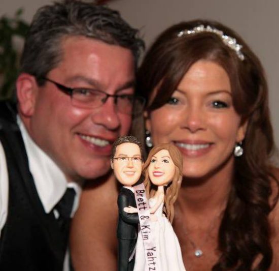 Happy couple celebrating with wedding cake toppers, smiling for the camera
