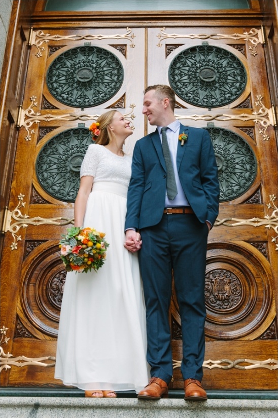 Newlyweds pose before ornate wooden doors together