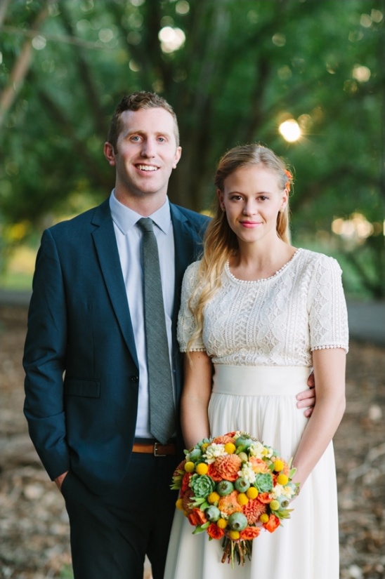 Happy newlywed couple posing with bouquet