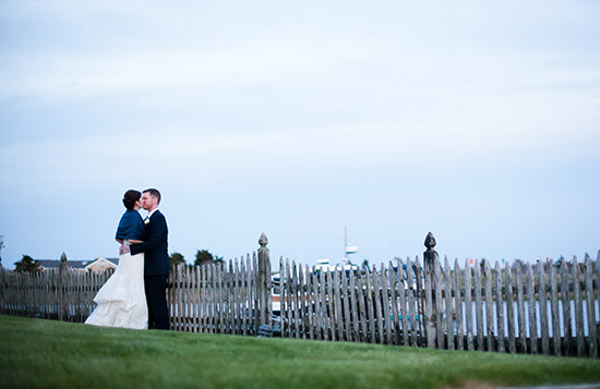 Bride and groom kissing by a wooden fence
