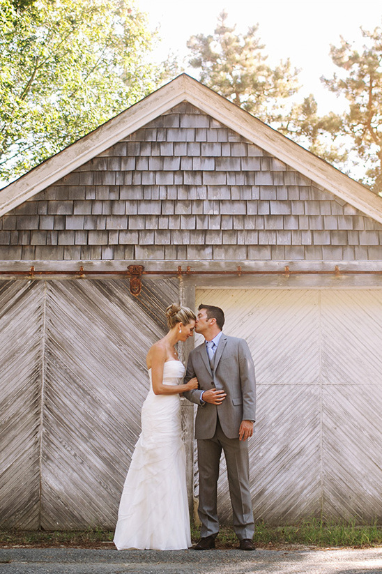 Bride and groom share a tender kiss by rustic barn