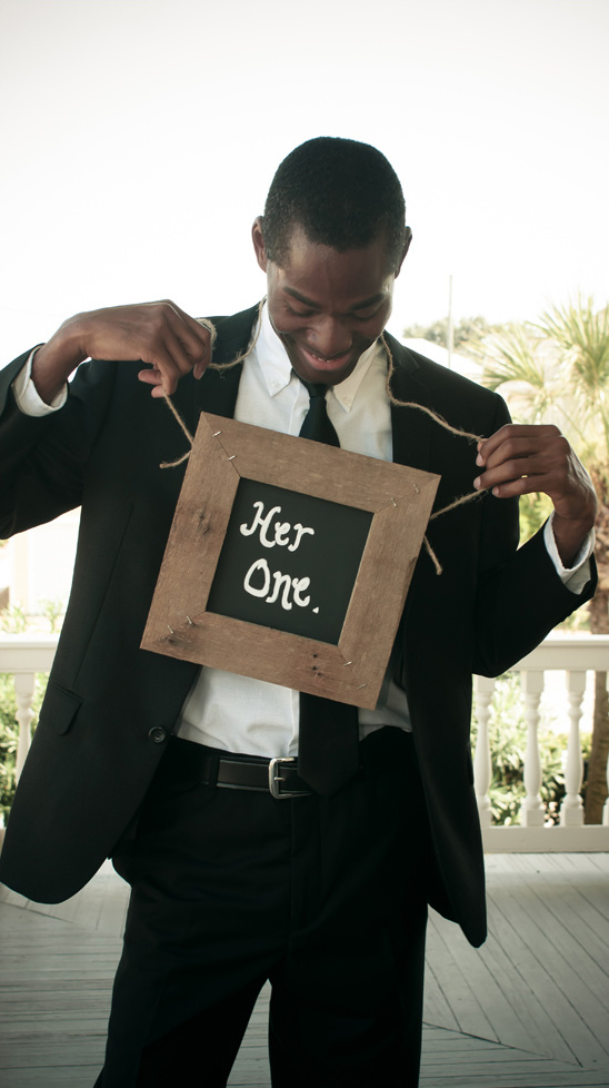 Smiling groom holds Her One sign at wedding