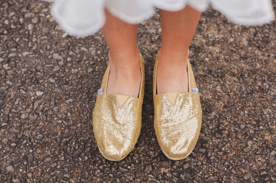 Woman wearing sparkly gold shoes standing on textured ground