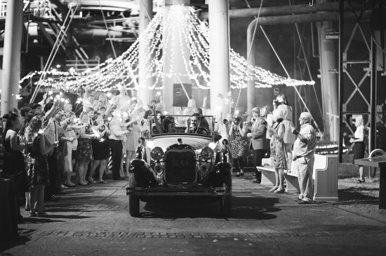Couple in vintage car exiting wedding with sparklers
