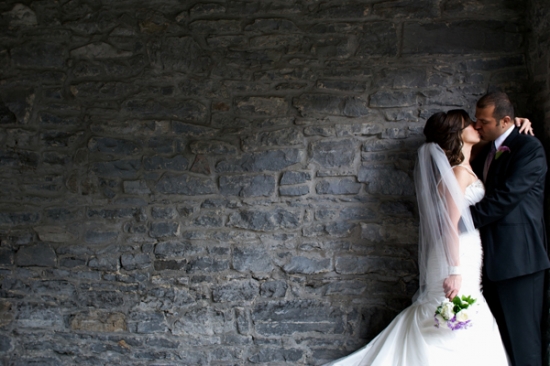 Couple kissing by stone wall wedding photo