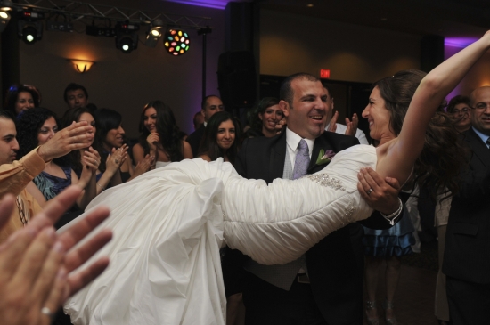 Groom holding bride at wedding reception party