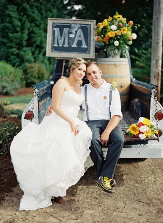 Happy couple poses on vintage truck, rustic wedding