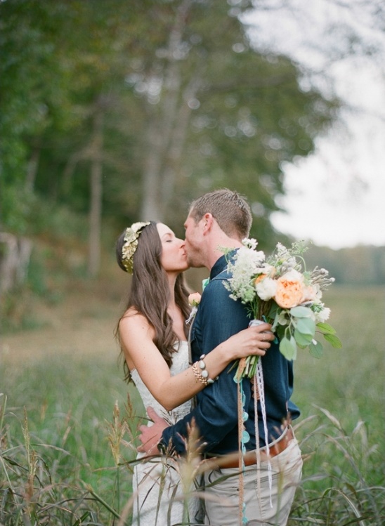 Bride and groom kissing in a field on their wedding day