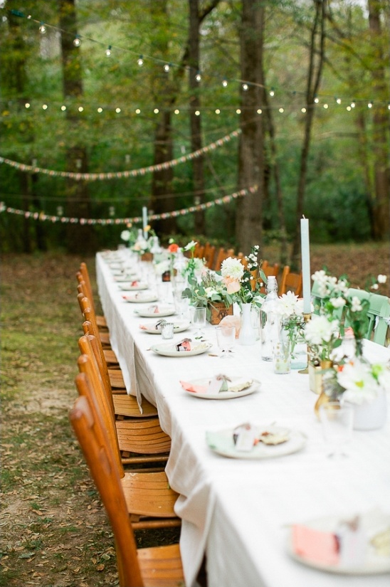 Outdoor wedding table setting with floral arrangements and string lights