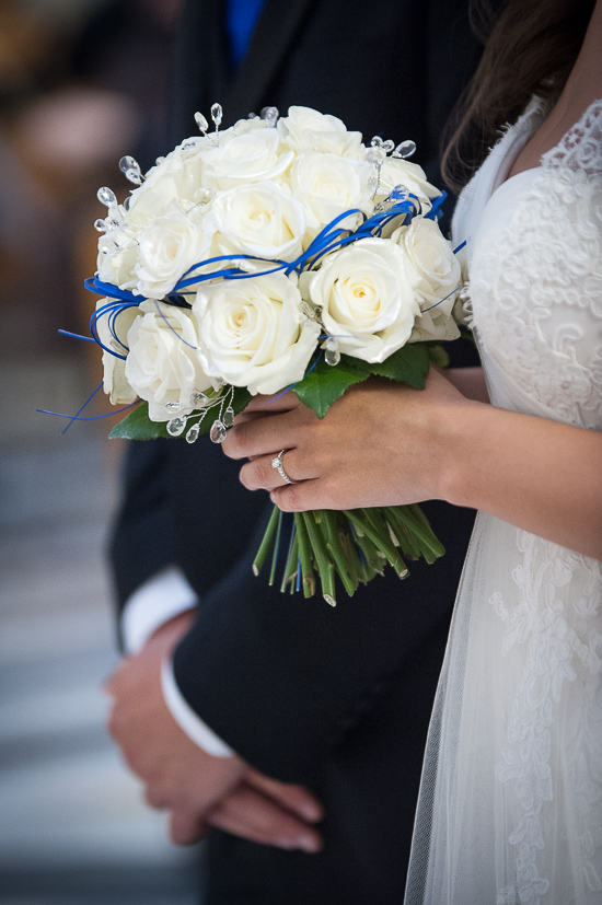 Bride holds white rose bouquet with blue ribbon
