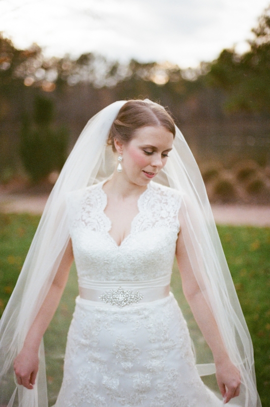 Bride in white lace wedding dress and veil outdoors