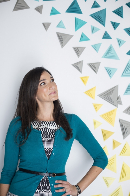 Woman looking up at colorful triangle art on a white wall