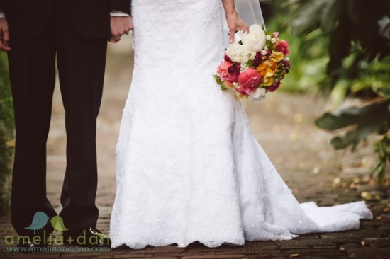 Bride holding a vibrant bouquet, wedding dress with groom holding hands