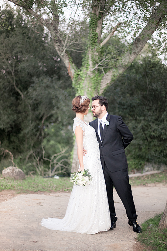 Elegant couple embracing under a tree at their outdoor wedding