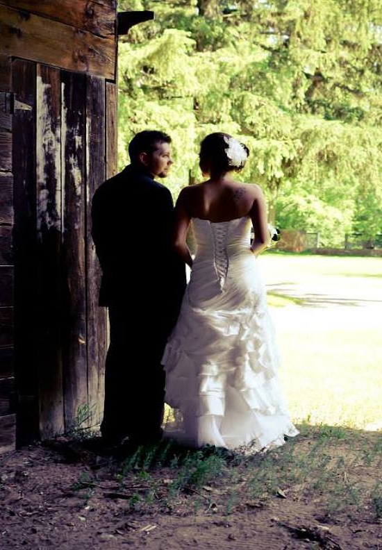 Bride and groom pose near rustic doorway