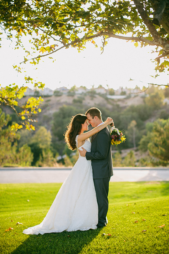 Newlyweds embrace in a sunlit park during a wedding ceremony