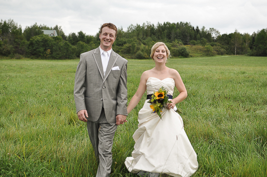 Newlyweds smiling and walking through a field on their wedding day