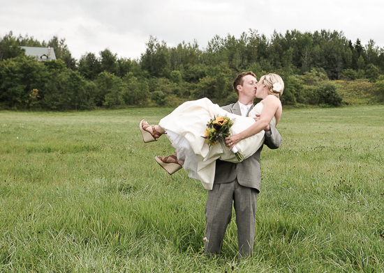 Newlyweds embrace in a kiss during a field wedding ceremony
