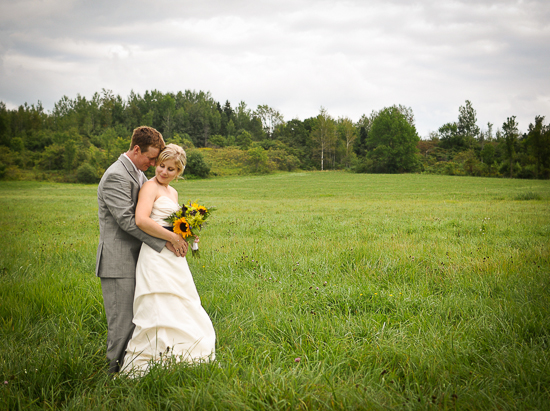 Couple embraces in a field on their wedding day, sunflowers