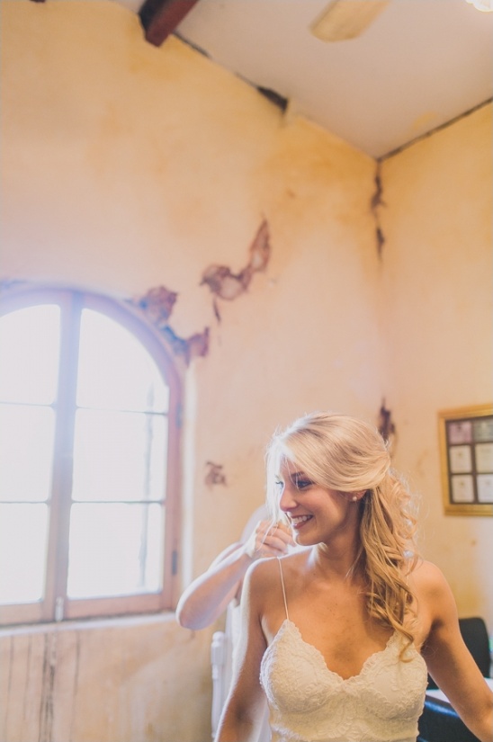 Smiling bride being helped into her wedding dress