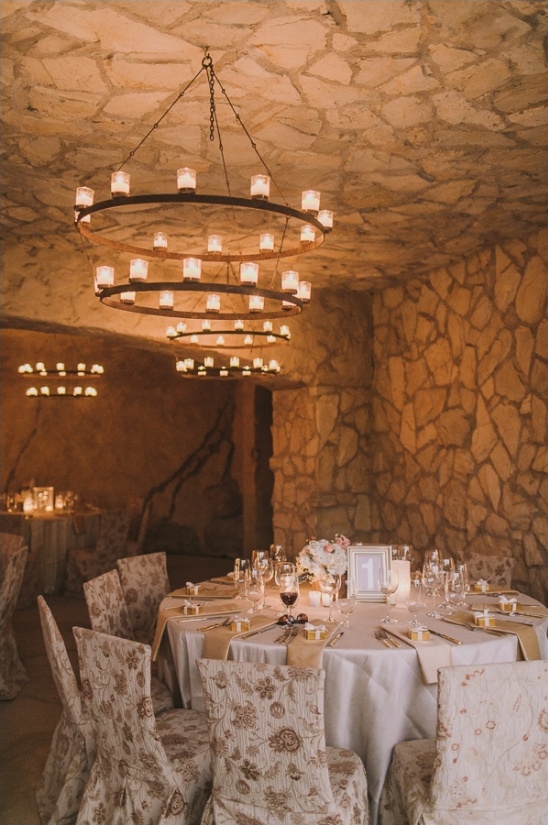 Romantic wedding reception setup in a stone-walled venue with chandelier lights