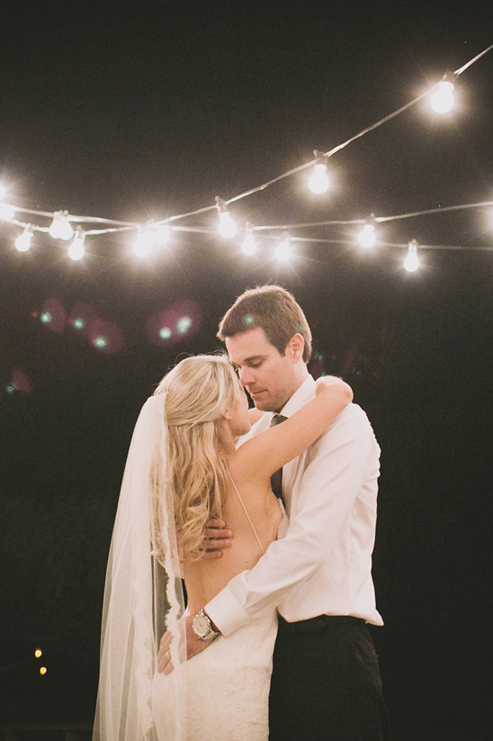 Bride and groom dance under string lights during their wedding