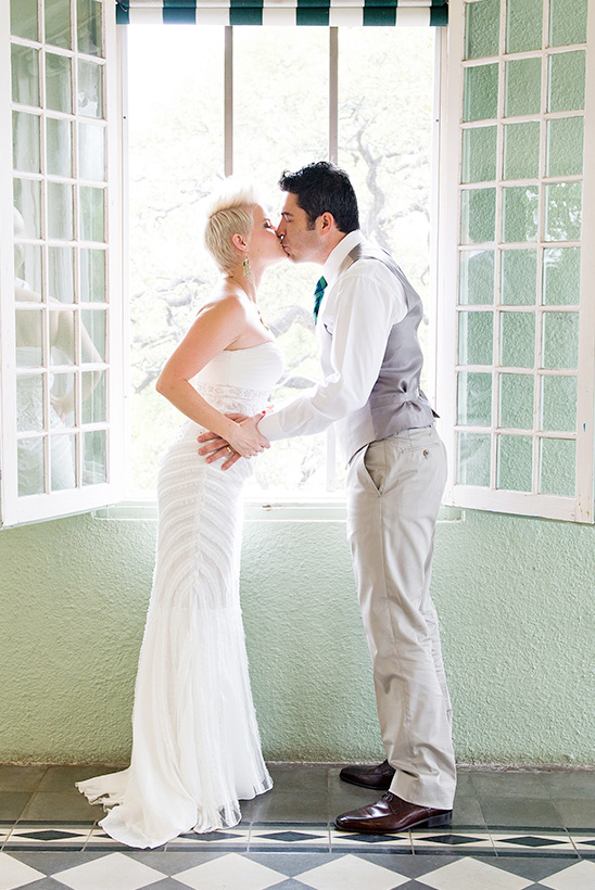 Bride and groom share a kiss by a window