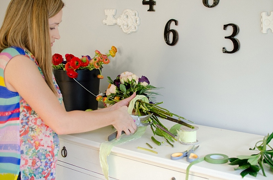Woman arranging fresh flowers on white dresser