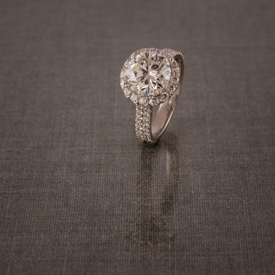 Elegant diamond engagement ring with sparkling halo on gray backdrop