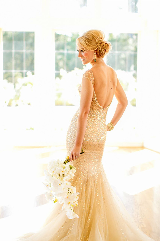Bride in a golden sequin wedding gown holding a white floral bouquet