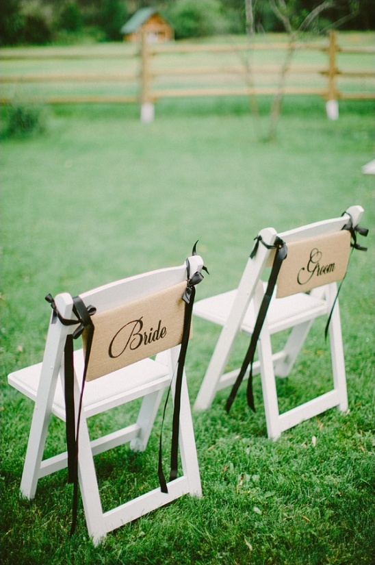 Wedding chairs reserved for the bride and groom decorated with ribbon