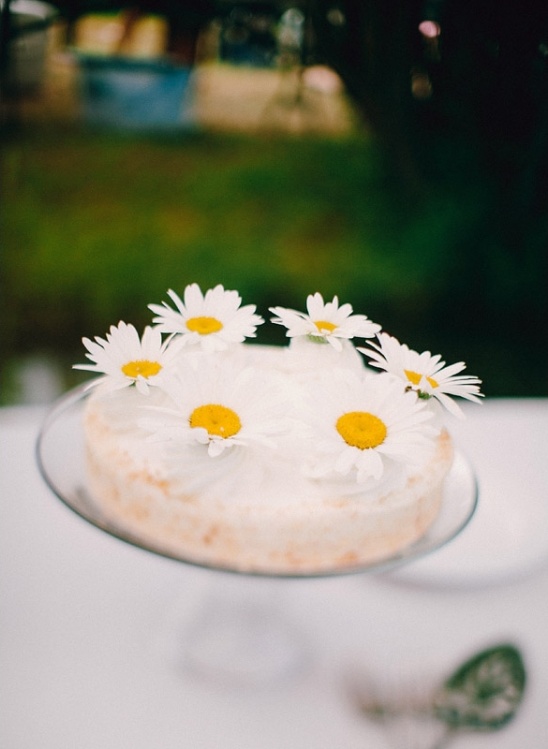 Daisy covered cake on a glass cake stand for a spring event