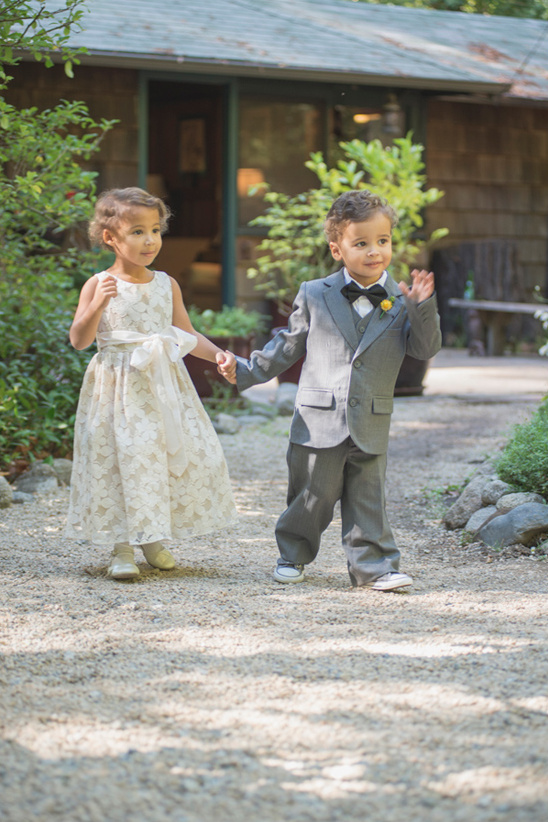 Cute flower girl and ring bearer holding hands outdoors