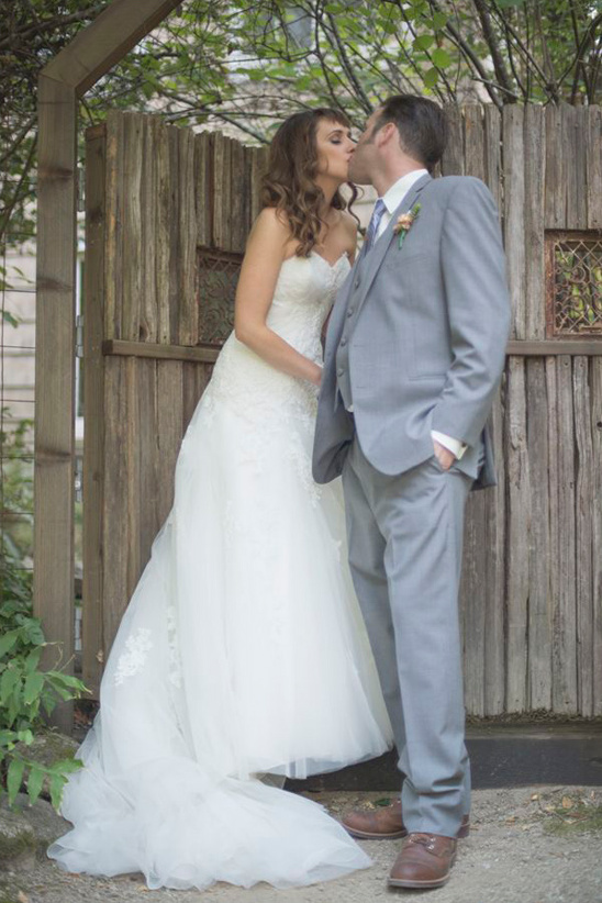 Bride and groom share a kiss on wedding day outdoor