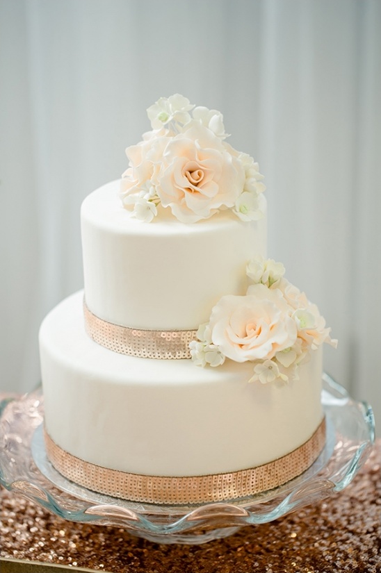 Elegant two-tiered wedding cake with floral decorations and gold accents