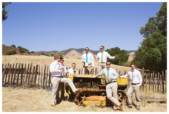 Groomsmen posing on a tractor in a sunny field with clear blue sky