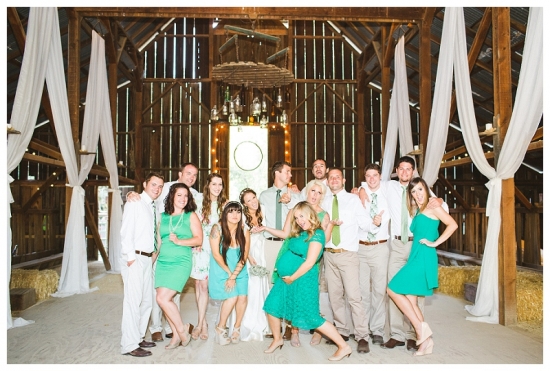Wedding party posing in a rustic barn for a joyful photo