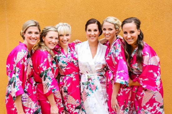 Bride and bridesmaids in floral robes smiling at wedding