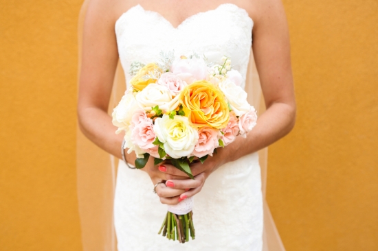 Bride holding a bouquet of peach yellow and white roses