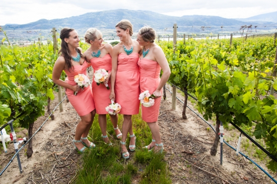 Bridesmaids in coral dresses with flowers in vineyard