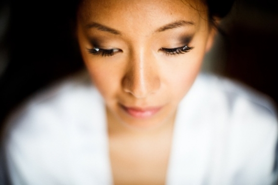 Woman with dramatic eye makeup looks down with soft focus