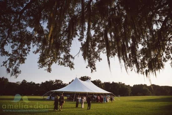 Large white tent in grassy field under trees