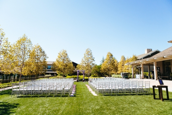 Outdoor wedding ceremony with rows of white chairs on green grass