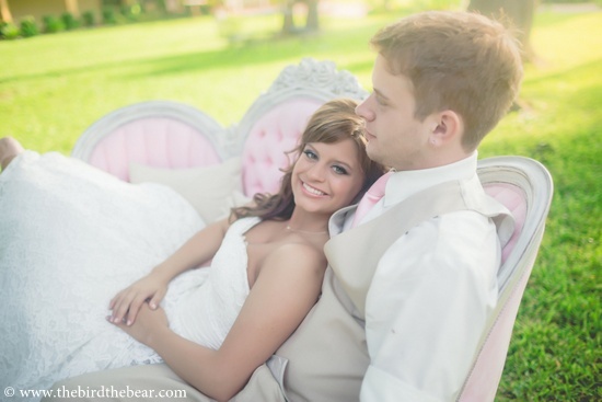Bride and groom relax on a pink couch after a wedding ceremony