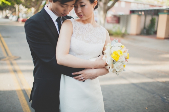 Loving Asian couple embracing on a sunny street wedding day
