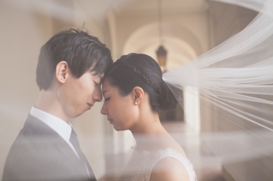 Bride and groom share an intimate moment, veiled and emotional