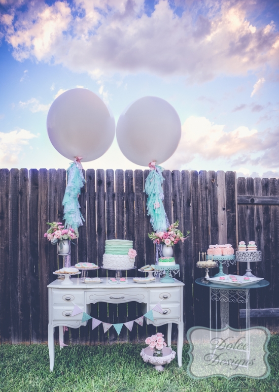Elegant dessert table with balloons, cake, and cupcakes