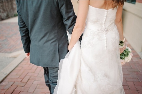 Bride and groom hold hands walking together on their wedding day