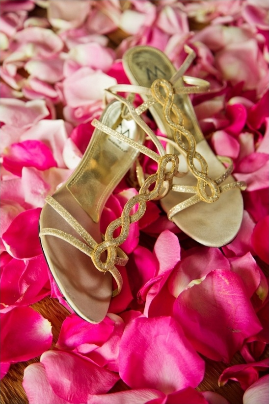 gold wedding shoes on a bed of pink rose petals