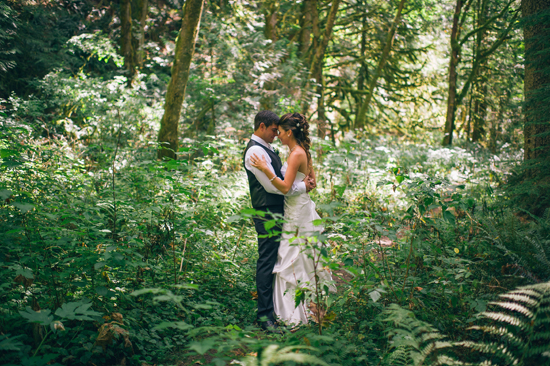 Romantic couple embracing in a lush green forest during their wedding